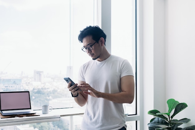 Serieuze man aan het werk met computer en telefoon met uitzicht op hoogbouw