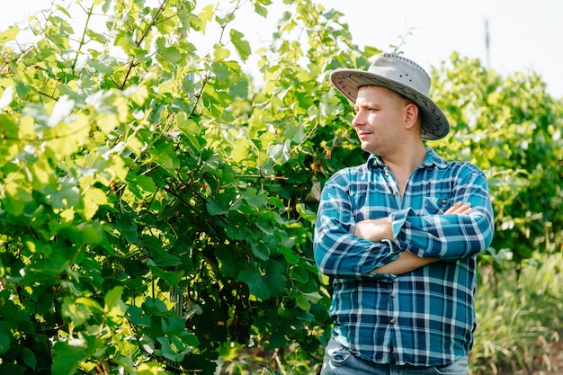 Serieuze moderne en jonge boer met hoed wijnmakerij en wijnmaker blanke man