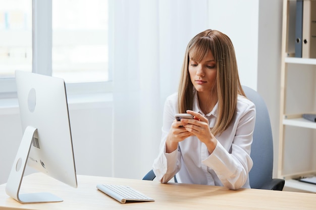 Serieuze schattige blonde zakenvrouw werknemer freelancer kijk naar telefoon typen bericht in licht modern kantoor werknemer doen breuk praten met zakenpartner lezen nieuws kopieer ruimte