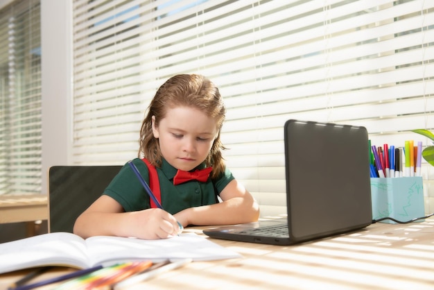 Serieuze schooljongen concentreerde zich op tekenen terwijl hij thuis in de buurt van een laptop zat