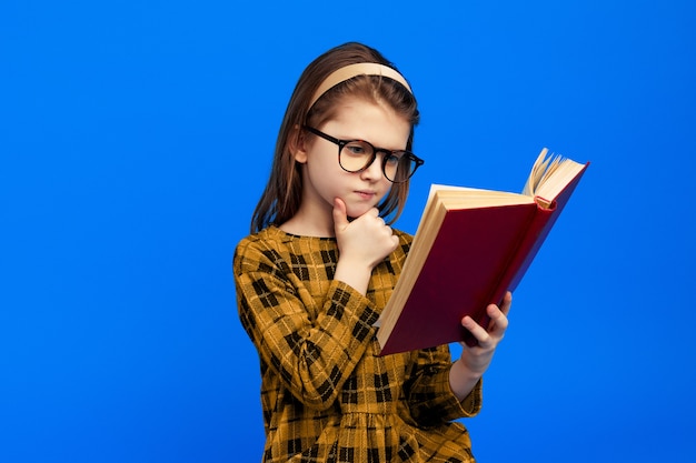 Serieuze slimme meid leest boek en raakt kin aan met hand draagt bril