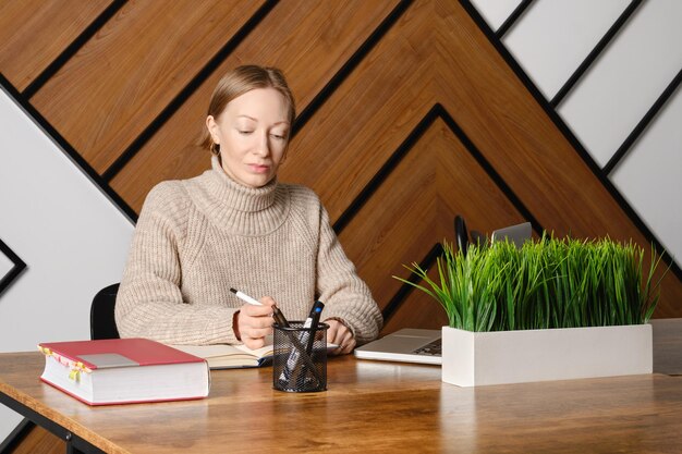 Serieuze volwassen vrouw werkt hard aan coworking en maakt aantekeningen in Kladblok