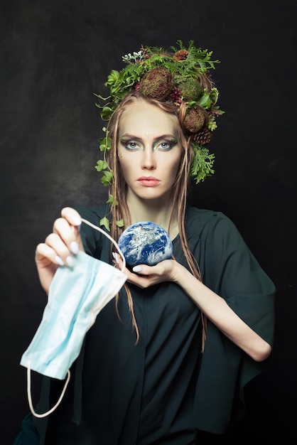 Serieuze vrouw die tijdens COVID-19 gebruikte beschermende medische maskers weggeeft en het concept van milieubescherming van de aarde omarmt Beeld geleverd door NASA