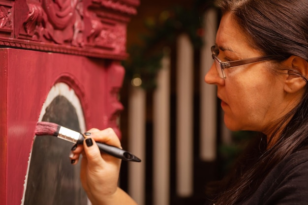 Serieuze vrouwelijke schilderij handgemaakte ornamenten van oude houten kastdeur met penseel in roze kleur Nieuw leven geven aan oude spullen Handrestauratie van oude meubels