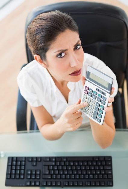 Photo serious accountant holding a calculator looking at camera