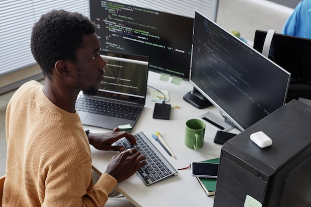 Фото Серьезный афроамериканский разработчик, работающий с кодами безопасности на компьютере на своем рабочем месте