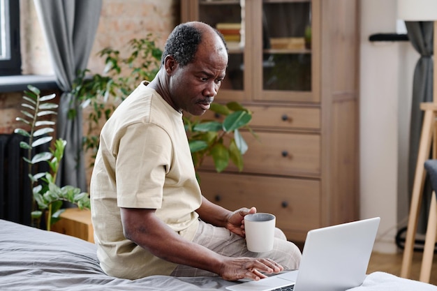 Serious african american pensioner looking at laptop screen during communication