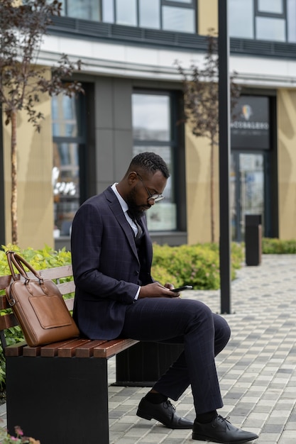 Serious african businessman in suit scrolling in smartphone