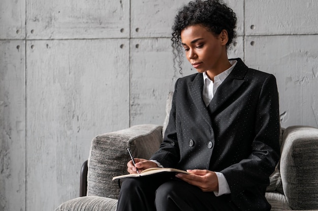 Serious African woman writing in armchair