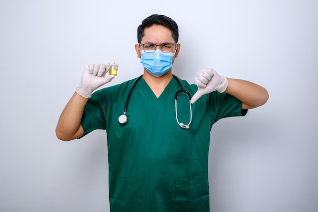 Serious asian doctor holding urine pot while showing thumb down showing bad result test