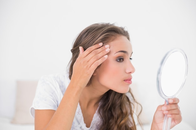 Serious attractive brunette looking at mirror