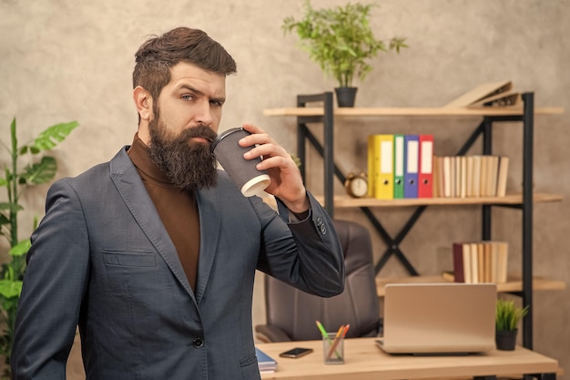 Foto un uomo d'affari barbuto che beve caffè da asporto in ufficio con spazio per copie da asporto