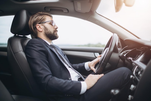 車を運転するフォーマルな服装で深刻なひげを生やした男