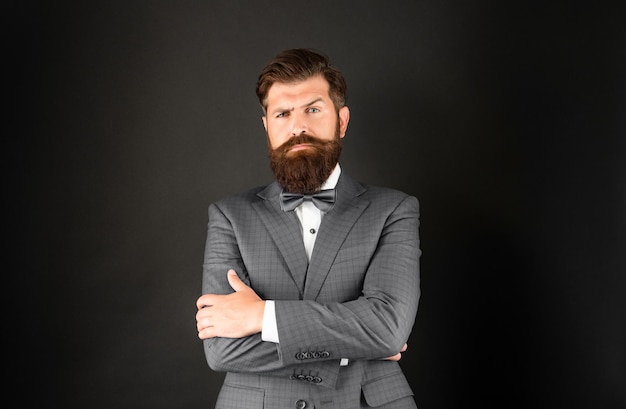 serious bearded man in tuxedo bow tie bride groom in formalwear on black background male formal fashion