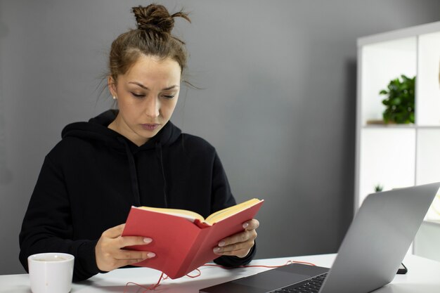 Libro di lettura serio della bella donna in copertina rossa durante la quarantena