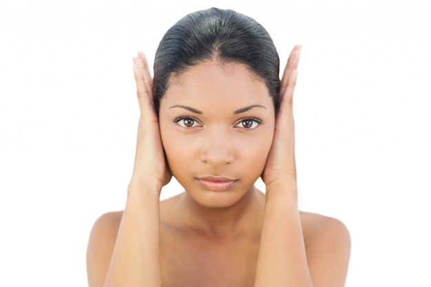 Serious black haired model blocking her ears