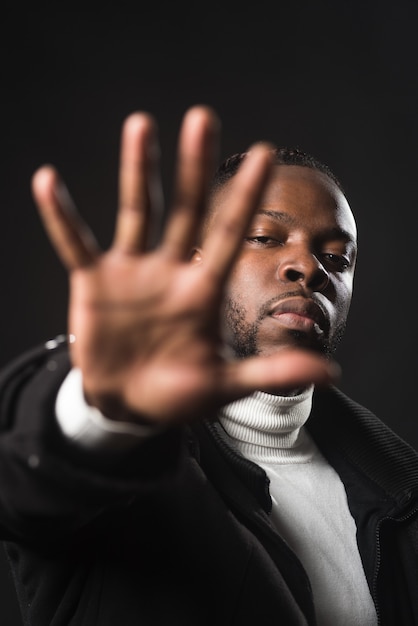 Serious black man telling you to stop with an open hand. close\
up. black background.