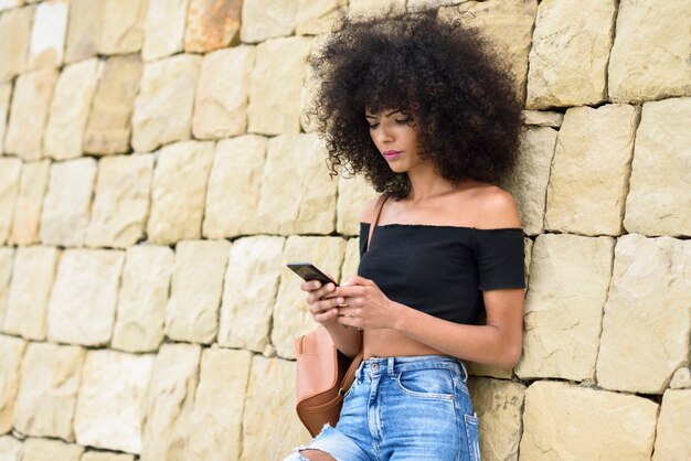 彼女のスマートフォンを屋外で見ている深刻な黒人女性