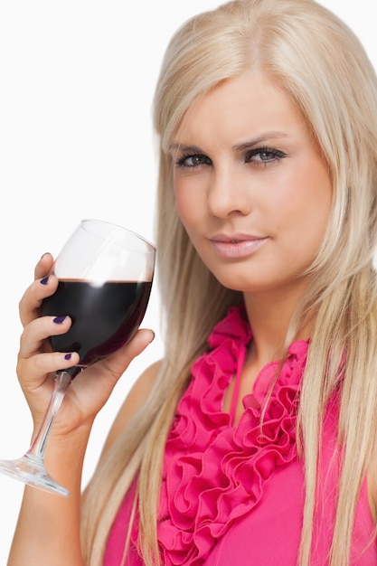 Серьезная блондинка, выпивая стакан красного вина