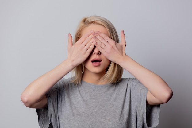 serious blonde woman in glasses on white wall
