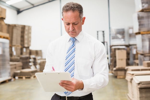 Serious boss writing on clipboard