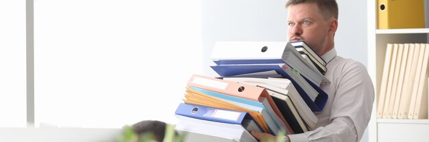 Serious brunette man holding pale of folders