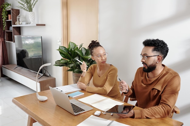 Serious business couple working at home sitting at desk and discussing problems