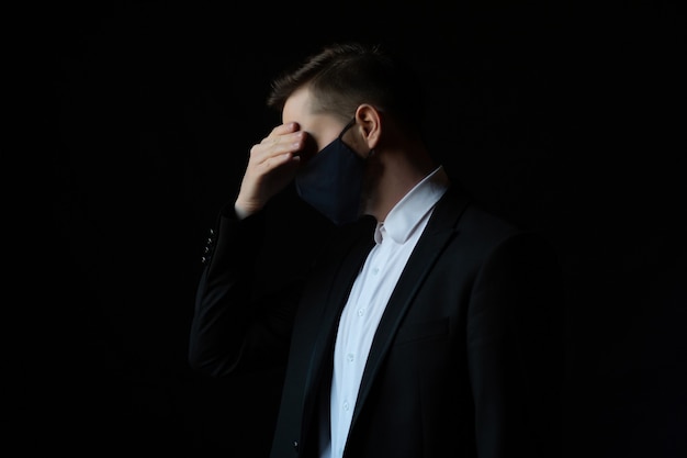 Serious business man in dark suit standing on black background looking down and feel stress isolated  