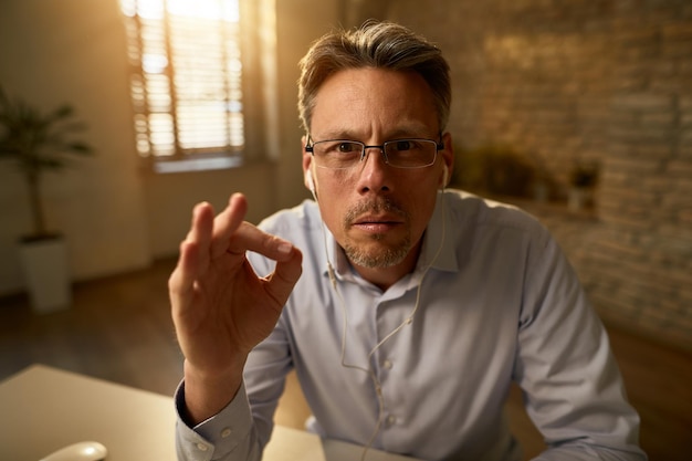 Serious businessman gesturing while working in the office and looking at the camera