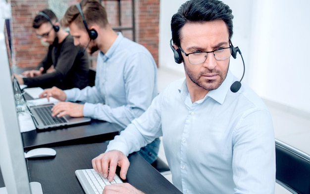 Serious businessman in a headset sitting at a desk