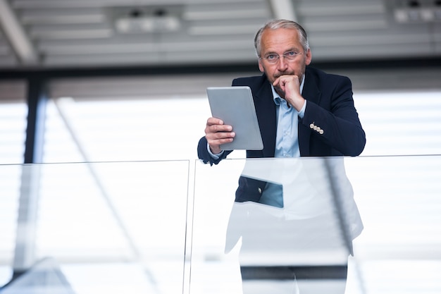 Serious businessman holding digital tablet