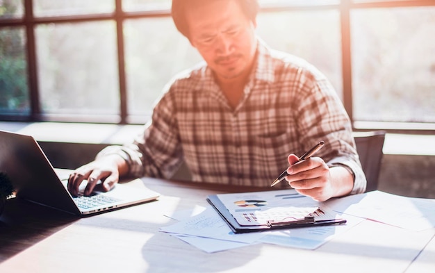 Serious businessman making notes on work desk working with paper documents focused employee doing economic research with laptop