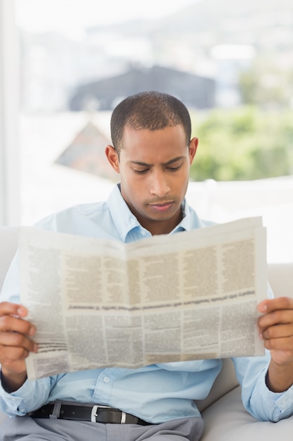 Serious businessman reading newspaper on the couch