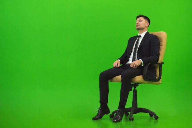 The serious businessman sit on the green background