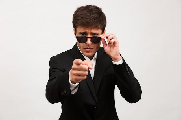 Serious businessman standing isolated wearing sunglasses.