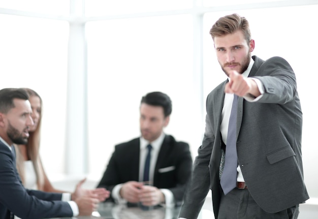 Serious businessman standing in the office and pointing at you