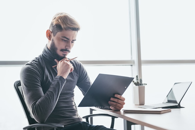 Serious businessman thinking hard of problem solution working in office with computer, documents, thoughtful trader focused on stock trading data analysis, analyzing forecasting financial rates