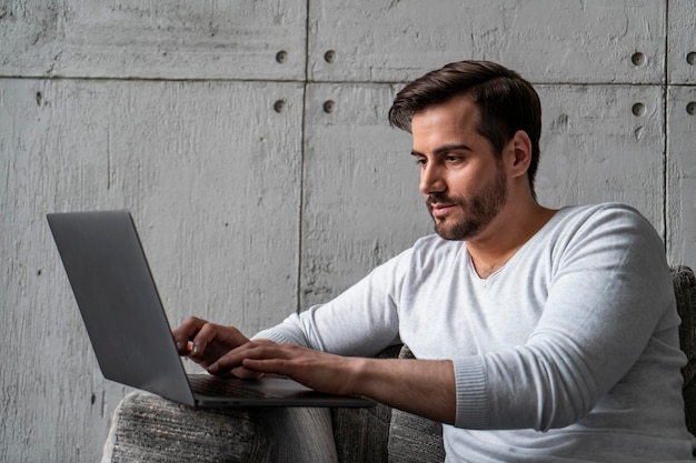 Serious businessman typing on laptop in armchair