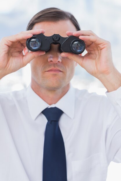 Photo serious businessman using binoculars