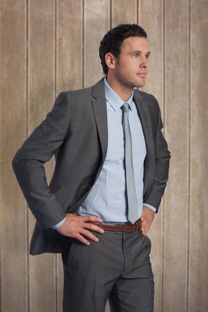 Photo serious businessman with hands on hips against wooden surface with planks