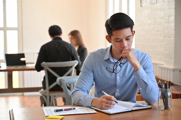 Serious businessman working on table in coworking space 