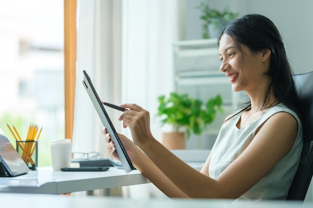 Serious businesswoman sitting in front of laptop computer at her workplace and reading financial reports