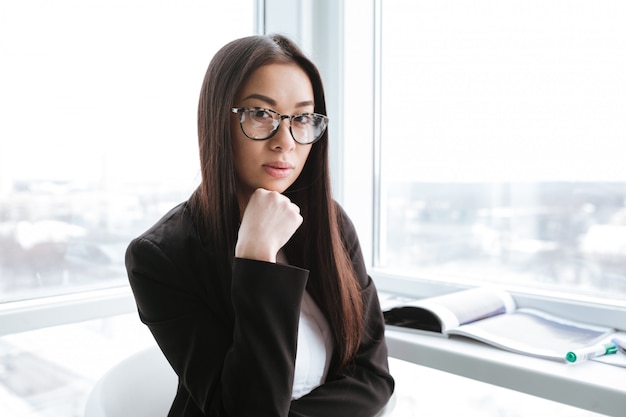 Serious businesswoman standing near the window in office