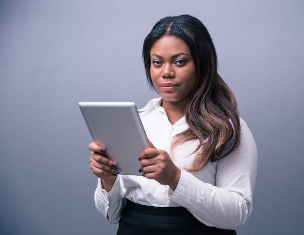 Serious businesswoman standing with tablet computer