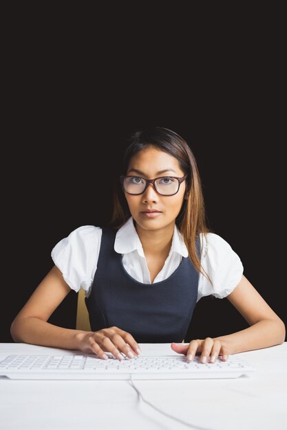 Serious businesswoman using a computer on black background