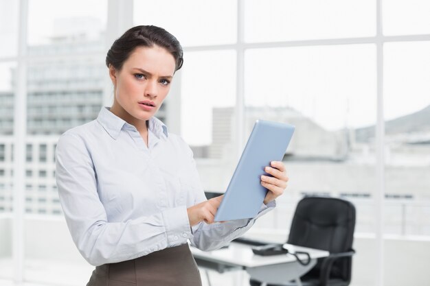 Serious businesswoman using table PC in office