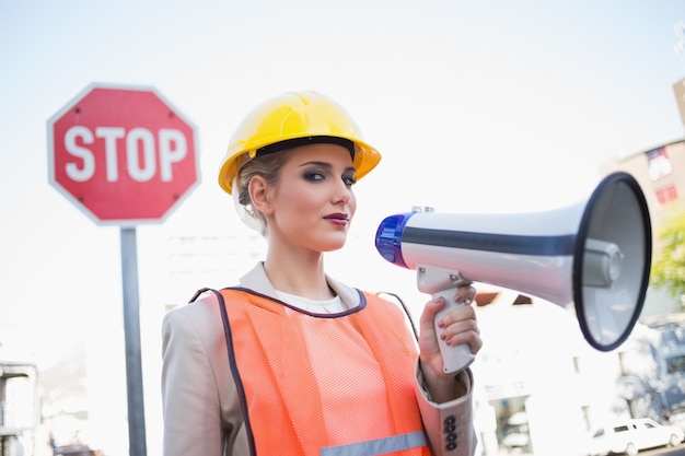 Serious businesswoman wearing builders clothes holding megaphone