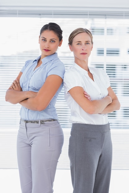 Serious businesswomen standing back-to-back