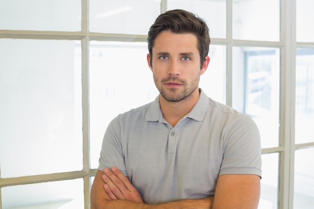 Serious casual businessman with arms crossed in office