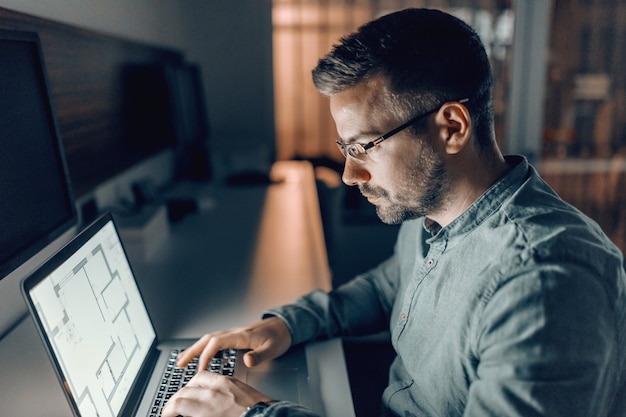 Photo serious caucasian architect with eyeglasses working on important project late at night in office.